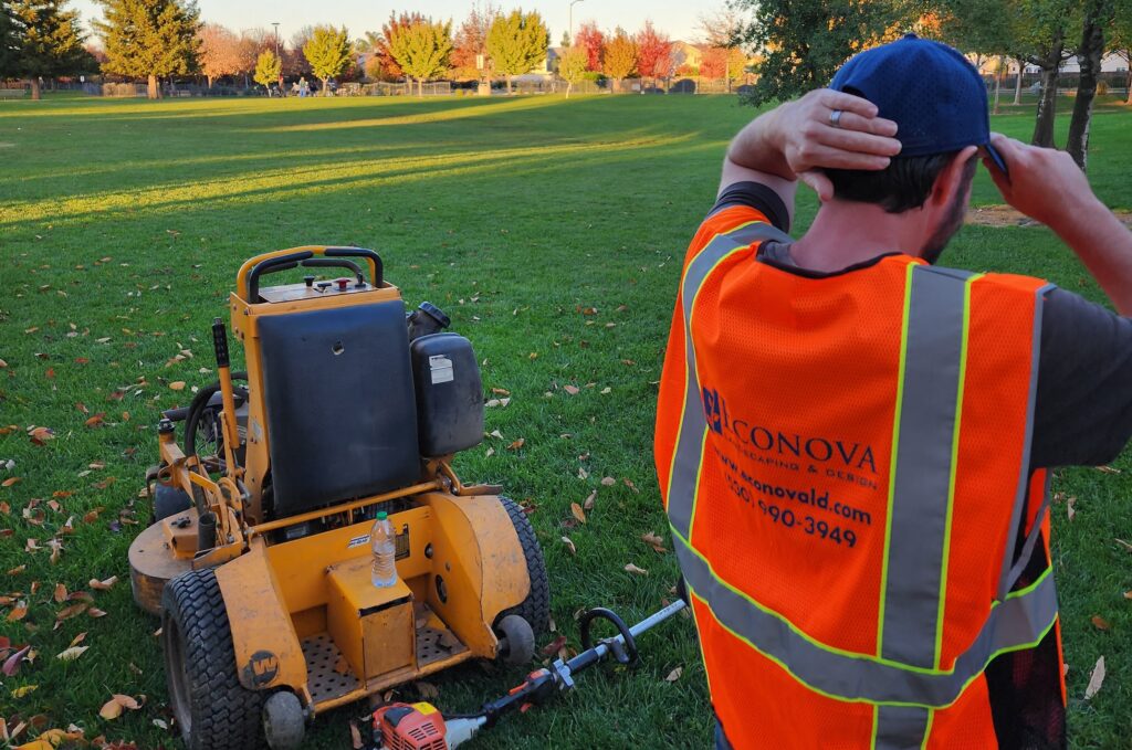 Groundskeeper in orange vest by mower