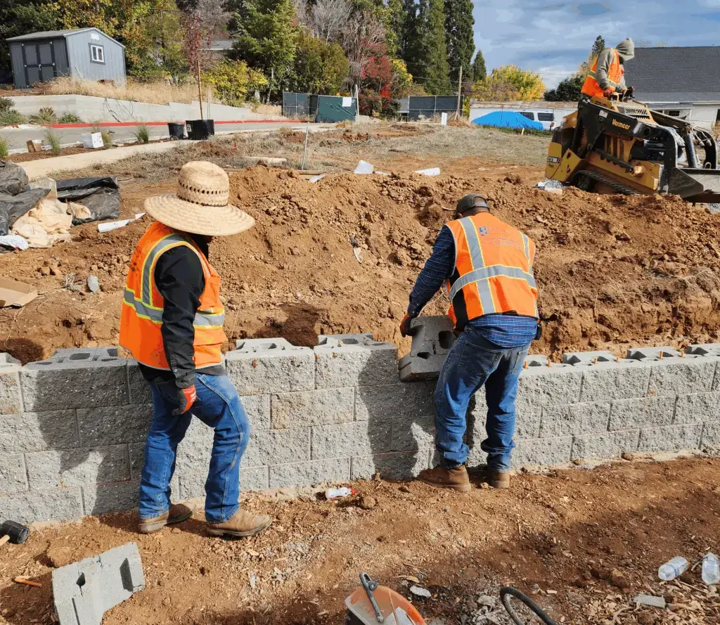 Construction workers building concrete block retaining wall